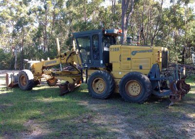 A yellow and black tractor is parked in a grassy area.