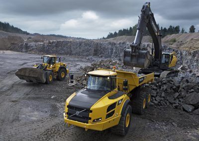 A yellow dump truck is being loaded with rocks in a quarry.