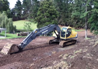 A volvo excavator is moving dirt on a dirt road.