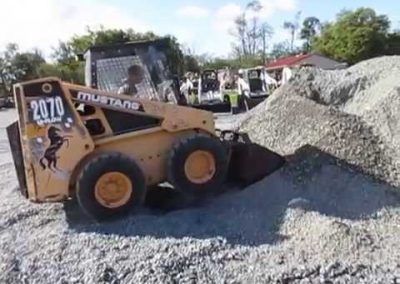 A mustang bulldozer is loading a pile of gravel into its bucket.