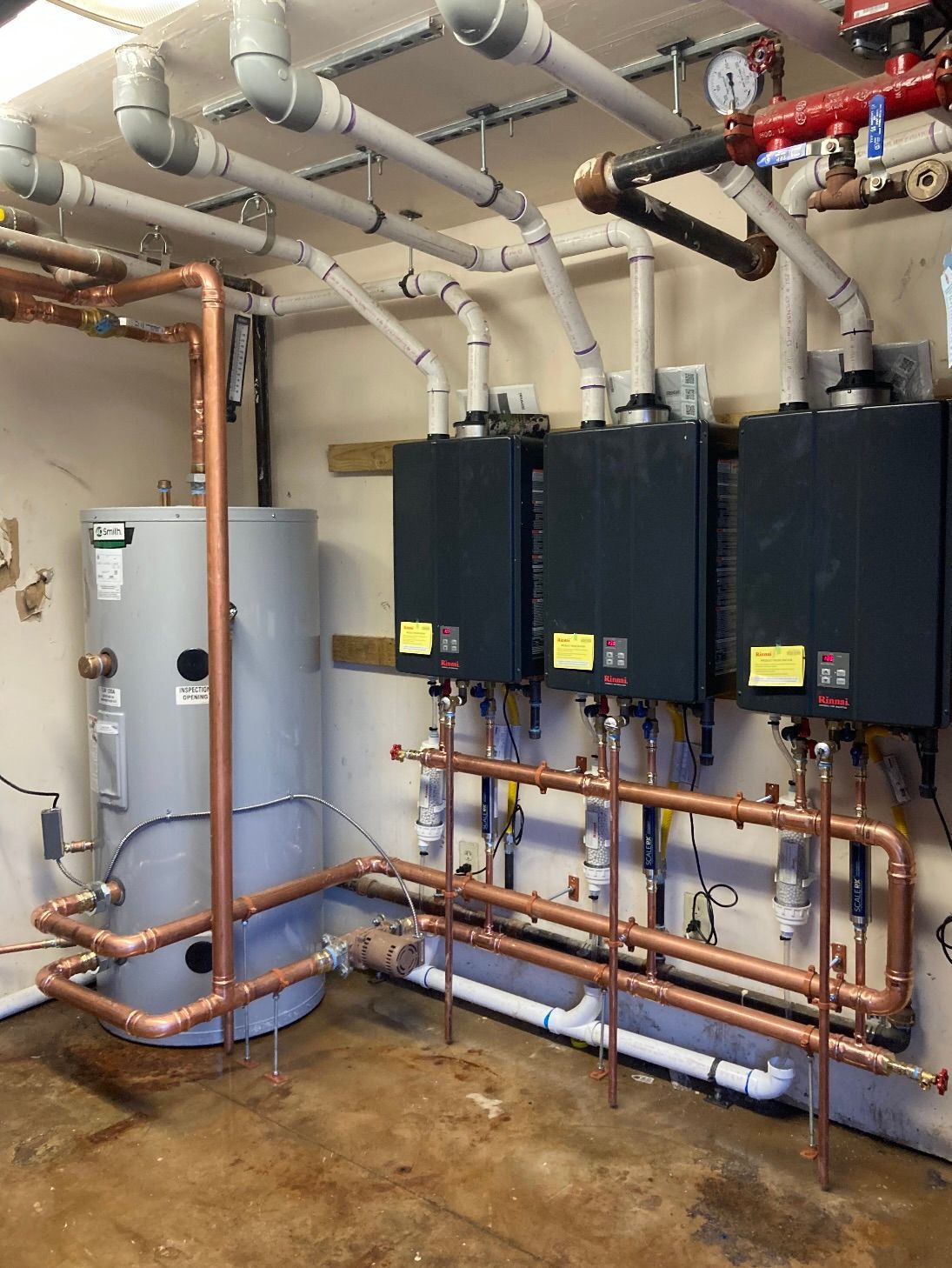 Copper pipes and water heaters installed in a mechanical room.