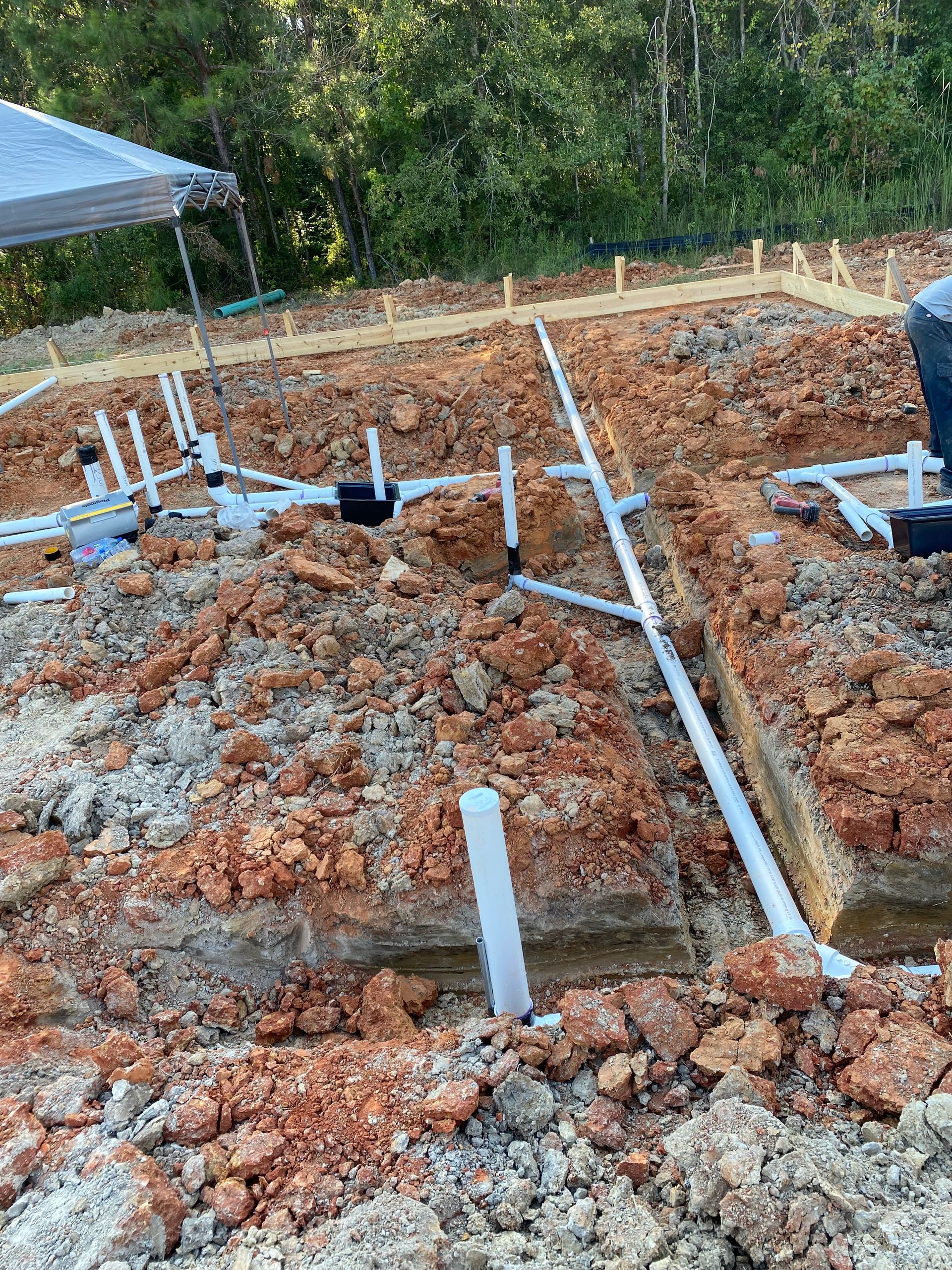 Plumbing pipes installed in red clay soil for a construction project, outdoors.