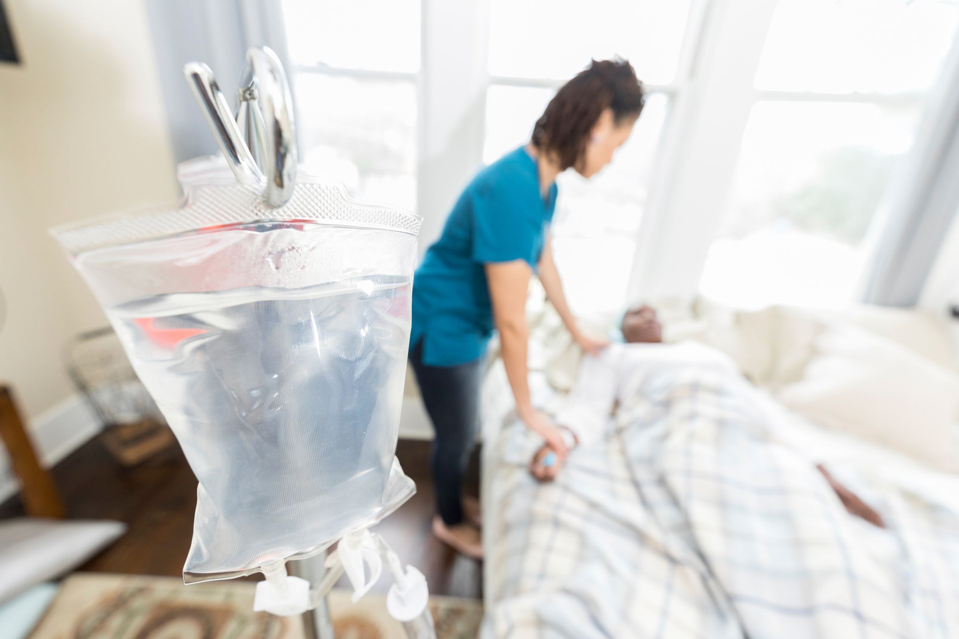A Nurse is Standing next to a Patient in a Hospital Bed | Lenexa, KS | Infuzion Oncology Solutions