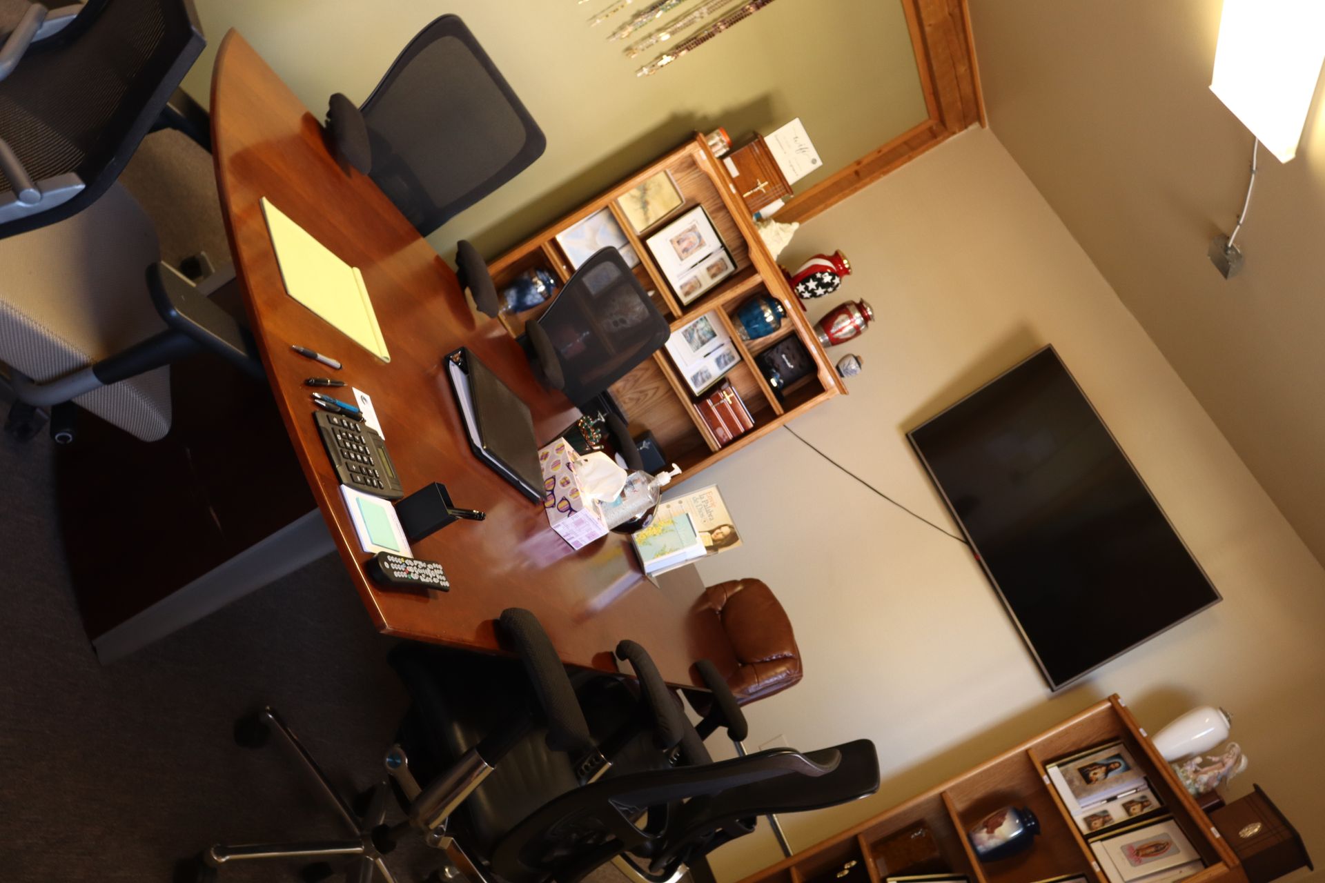 An office with a desk and chairs and a flat screen tv
