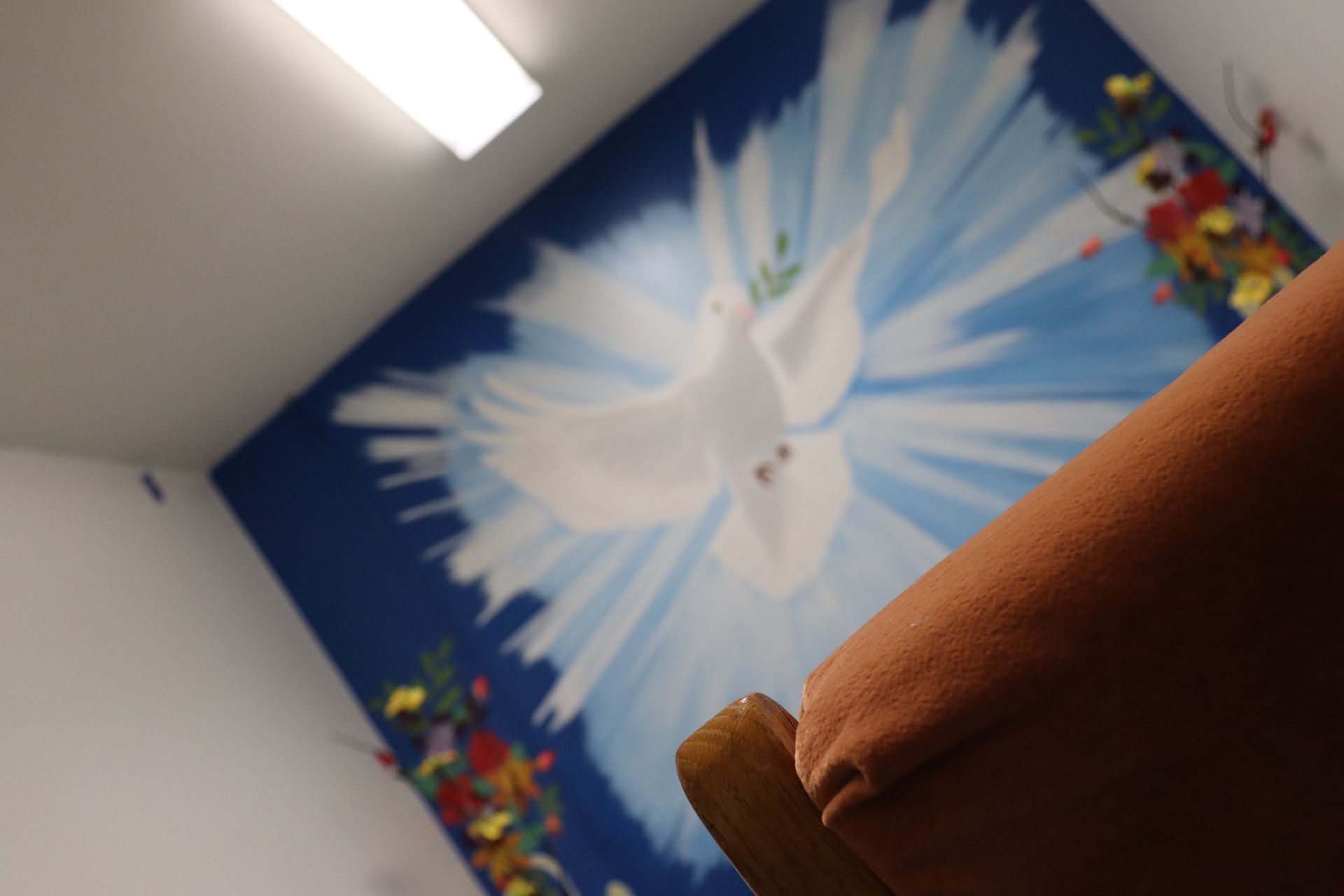 A room with a painting of a dove on the wall