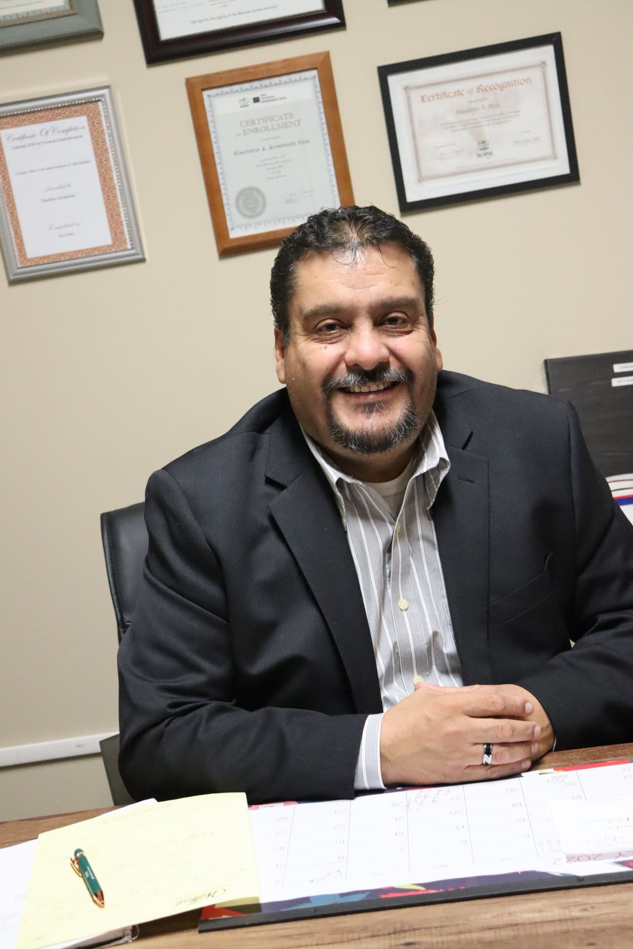 A man in a suit is sitting at a desk with a pen in his hand.