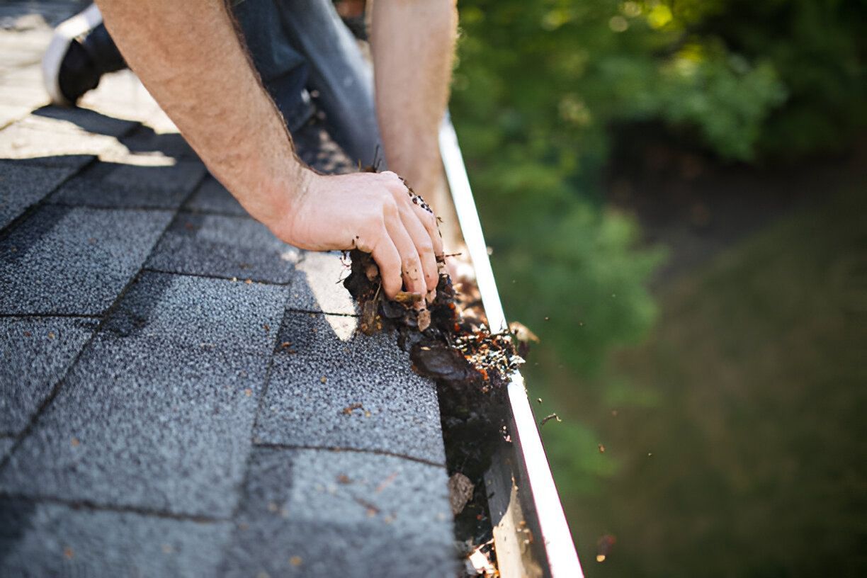 A man is cleaning a gutter on a roof.