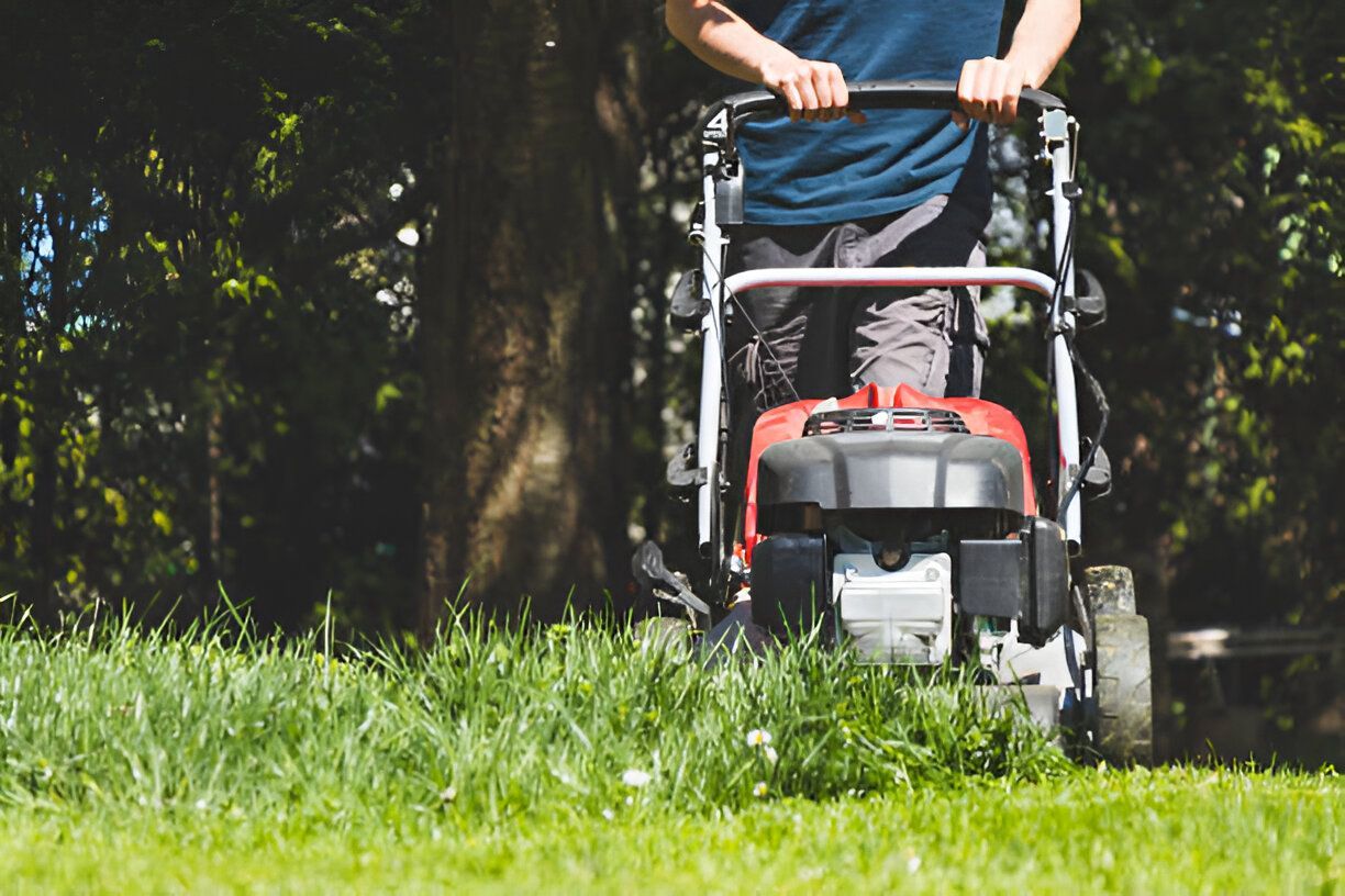 A man is mowing a lush green lawn with a lawn mower.