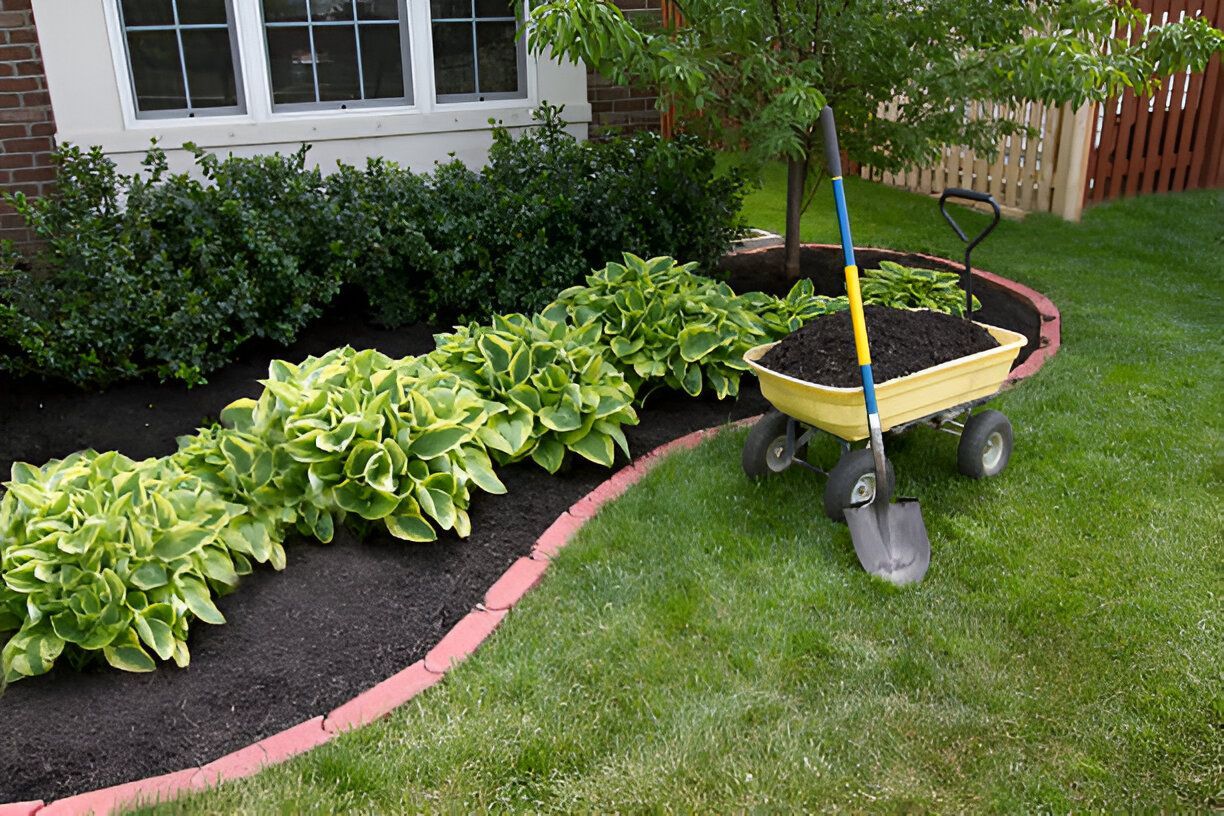 A wheelbarrow filled with dirt and a shovel in a garden.