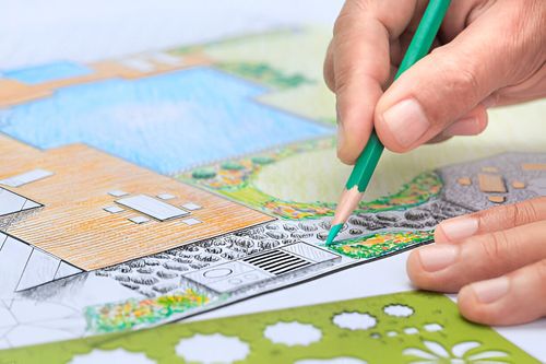 A person is drawing a landscape with a pencil on a piece of paper.