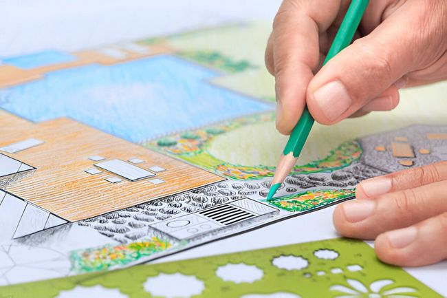 A person is drawing a landscape with a pencil on a piece of paper.