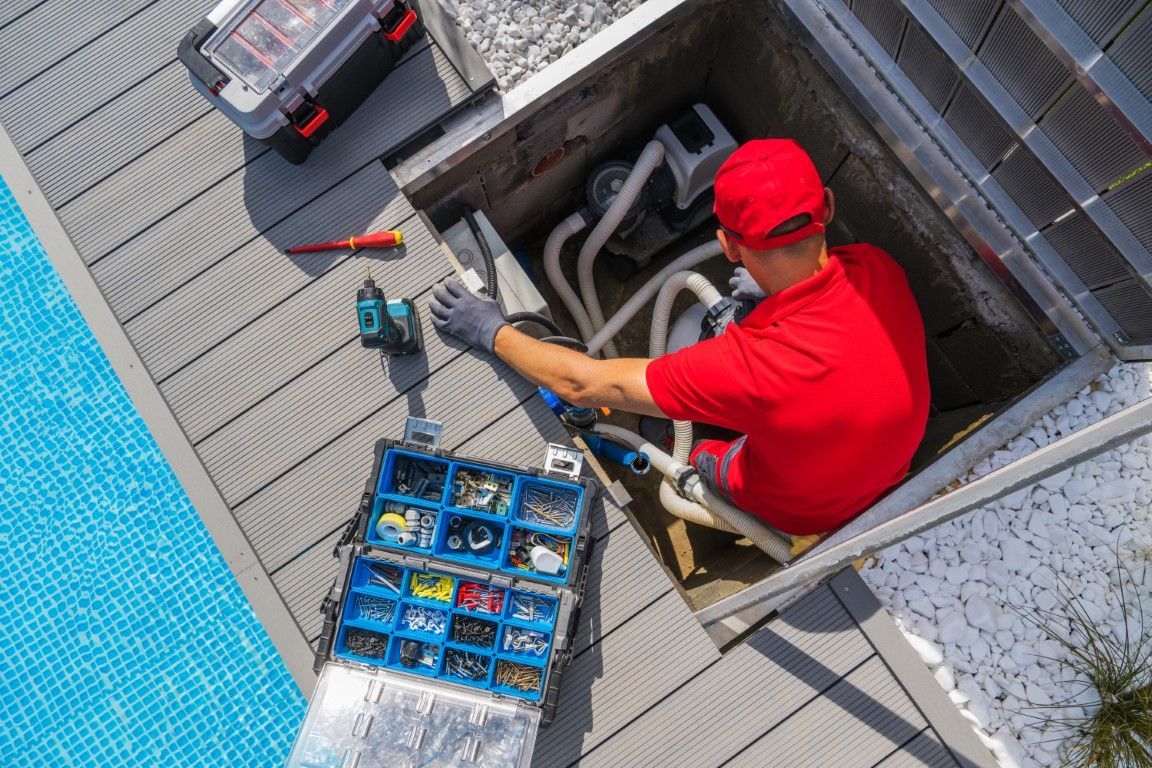 A man in a red shirt is working on a swimming pool.