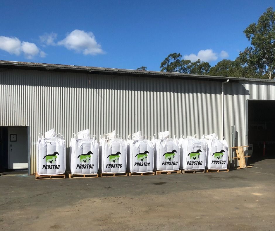 Bags of Pellets on Pallets in Front of a Corrugated Metal Building Under a Blue Sky — Prostoc In Bellbrook, NSW
