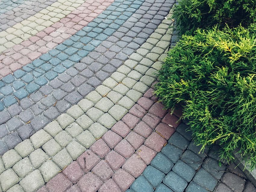A Row of Colourful Bricks on a Sidewalk Next to a Bush — HMJ Landscapes in Palm Beach, QLD