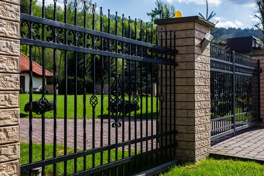 A Wrought Iron Fence is Surrounding a Brick Building — HMJ Landscapes in Mudgeeraba, QLD