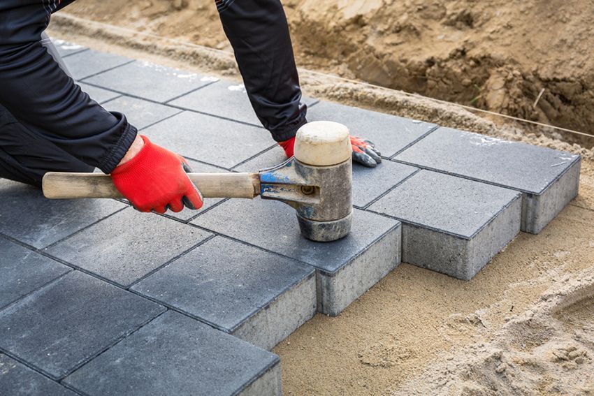 A Man is Using a Rubber Mallet to Hammer Bricks — HMJ Landscapes in Tweed Heads, NSW
