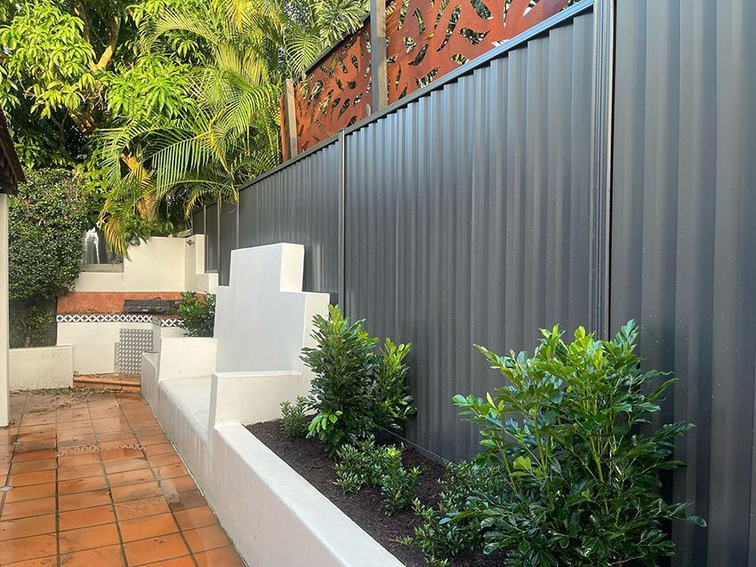 A Fence with a Planter in Front of It in a Backyard — HMJ Landscapes in Broadbeach, QLD