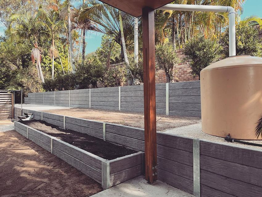 A Large Brown Water Tank is Sitting Next to a Fence in a Backyard — HMJ Landscapes in Broadbeach, QLD