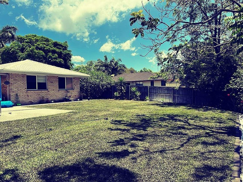 A House with a Fence and a Lush Green Yard — HMJ Landscapes in Palm Beach, QLD