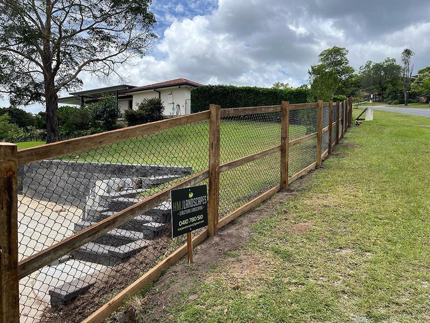 A Wooden Fence with a Chain Link Fence — HMJ Landscapes in Hope Island, QLD