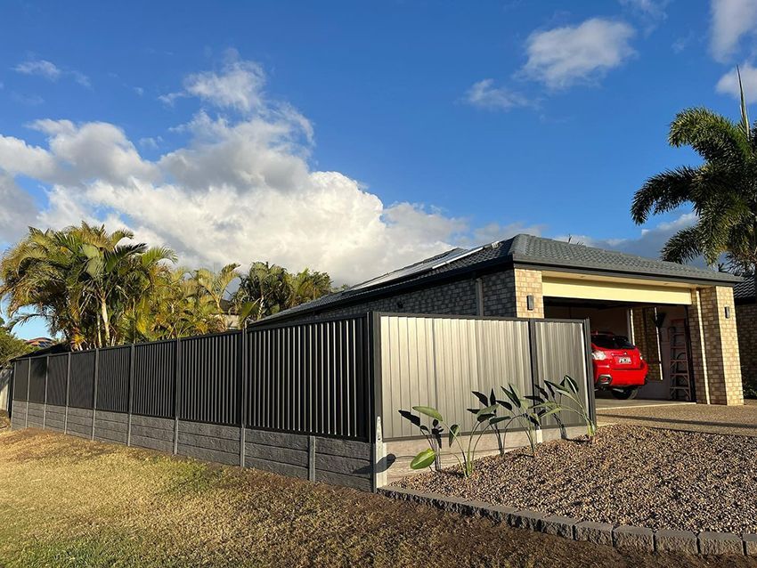 A Red Car is Parked in the Driveway of a House Behind a Fence — HMJ Landscapes in Palm Beach, QLD