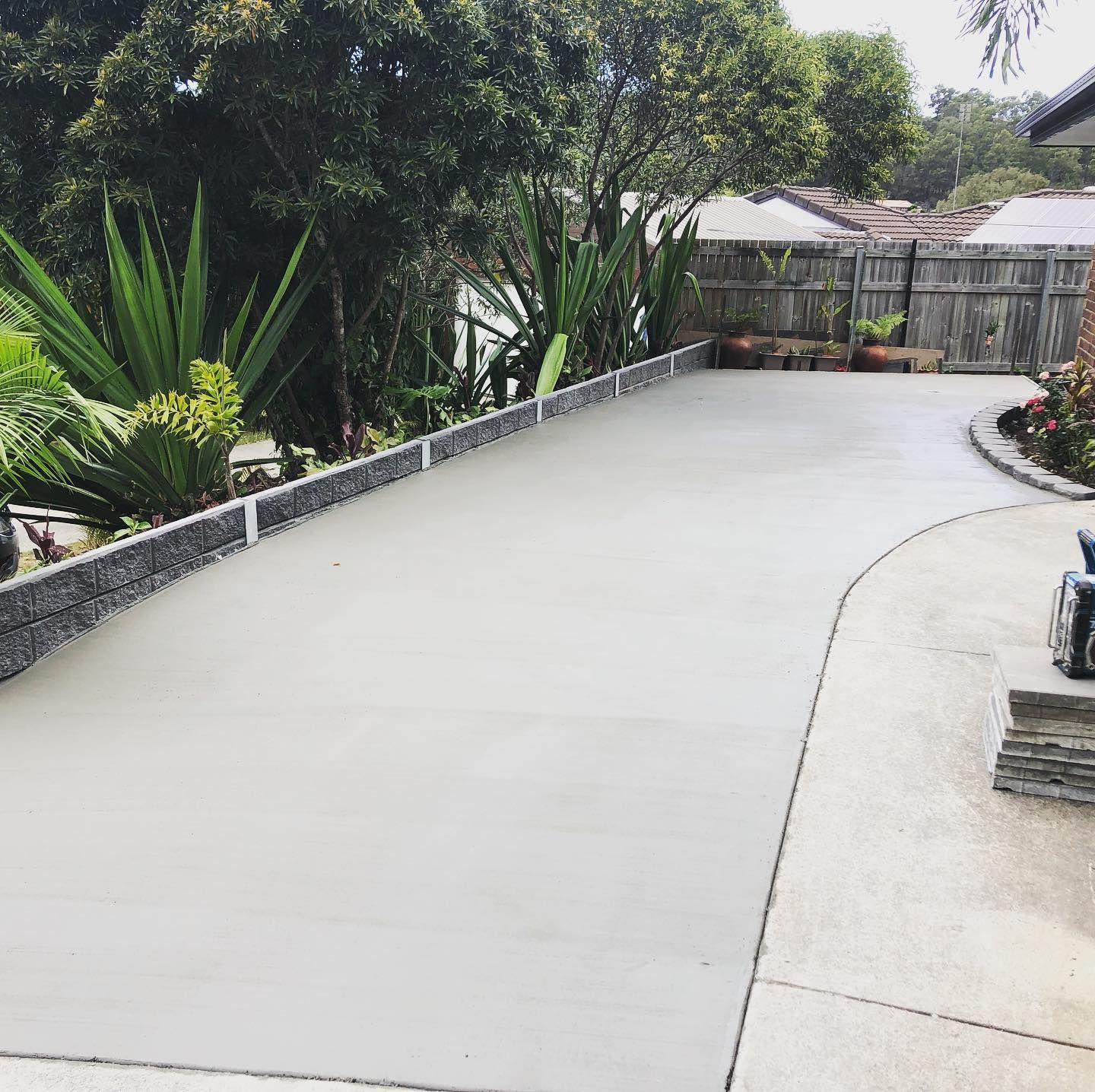A Person is Spreading Concrete on the Floor with a Trowel — HMJ Landscapes in Broadbeach, QLD