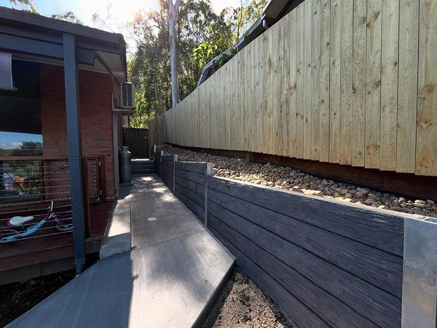 A Wooden Fence Surrounds a Concrete Walkway Leading to a House — HMJ Landscapes in Broadbeach, QLD