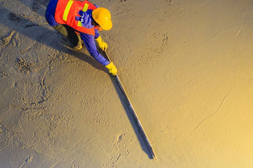 A Man Wearing a Hard Hat and Safety Vest is Working on Concrete — HMJ Landscapes in Palm Beach, QLD