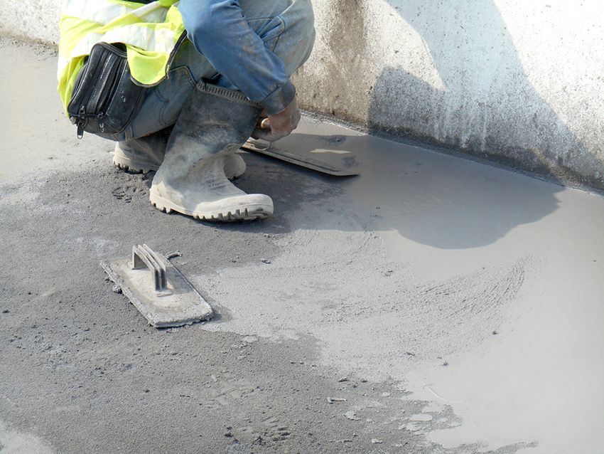 A Man is Kneeling Down and Using a Trowel on a Concrete Surface — HMJ Landscapes in Robina, QLD