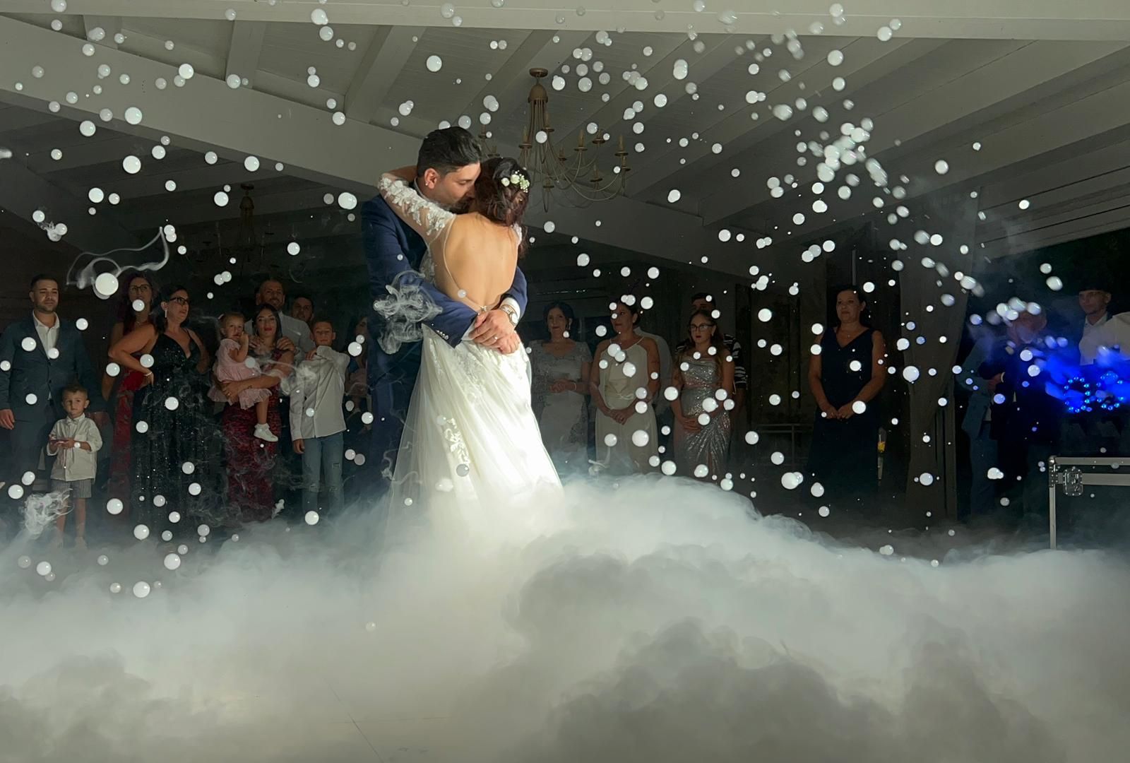 Gli sposi ballano a un matrimonio, circondati dalla nebbia e dai coriandoli che cadono.