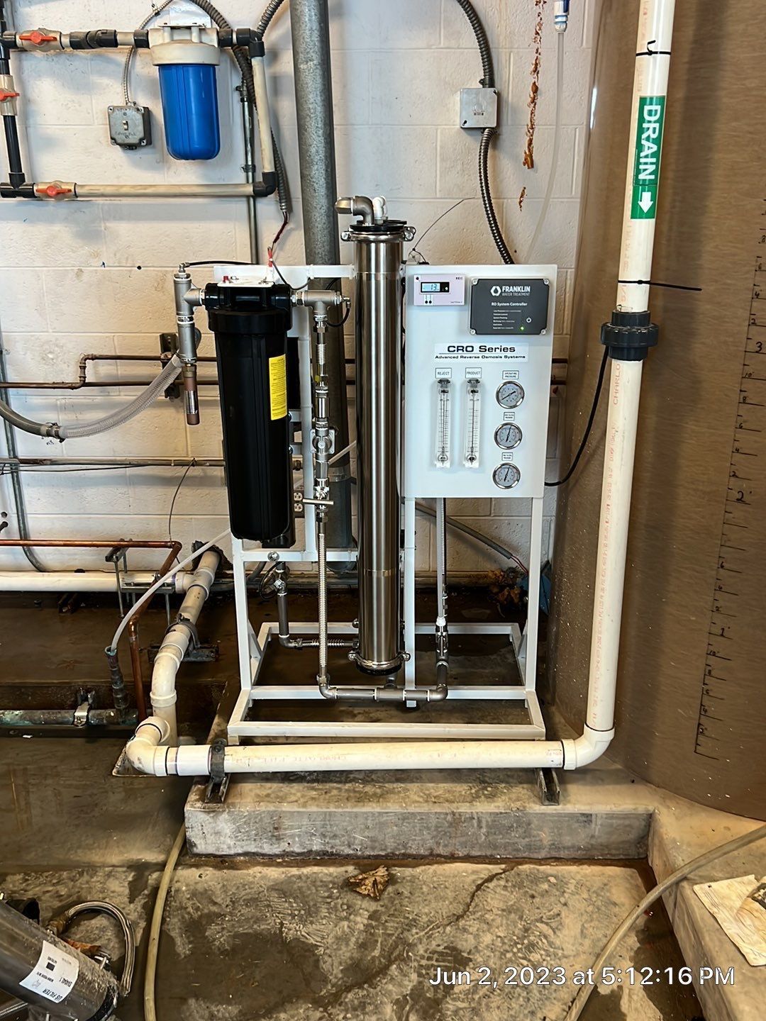 A water filter is sitting in a room next to pipes