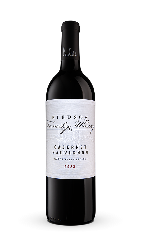 Black wine bottle with white label, standing on a plain white background.