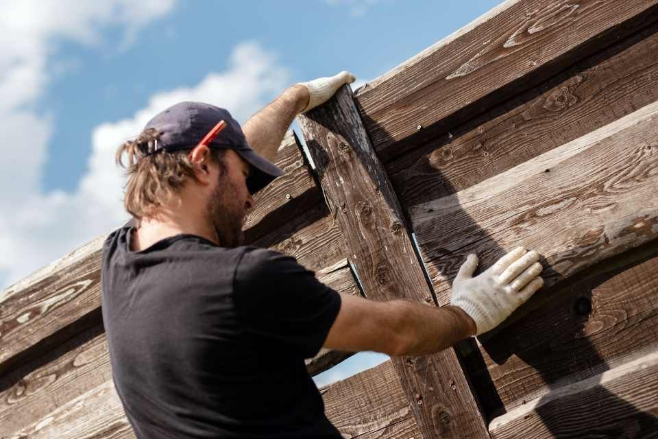 Man builds sections of fence around his yard out of planks