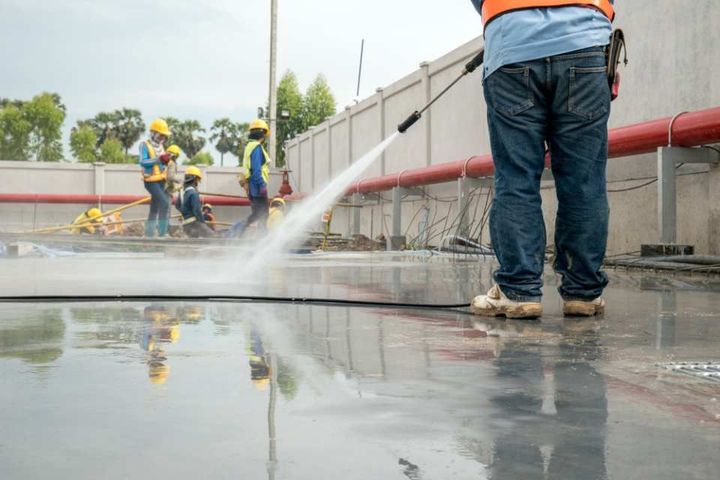 Construction worker concrete floor cleaning with high pressure water jet