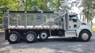 A white dump truck is parked in a gravel lot.