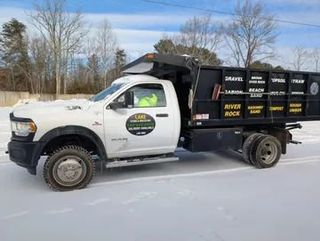 A white dump truck is driving down a snowy road.