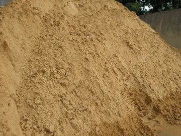A pile of sand is sitting on top of a pile of dirt.