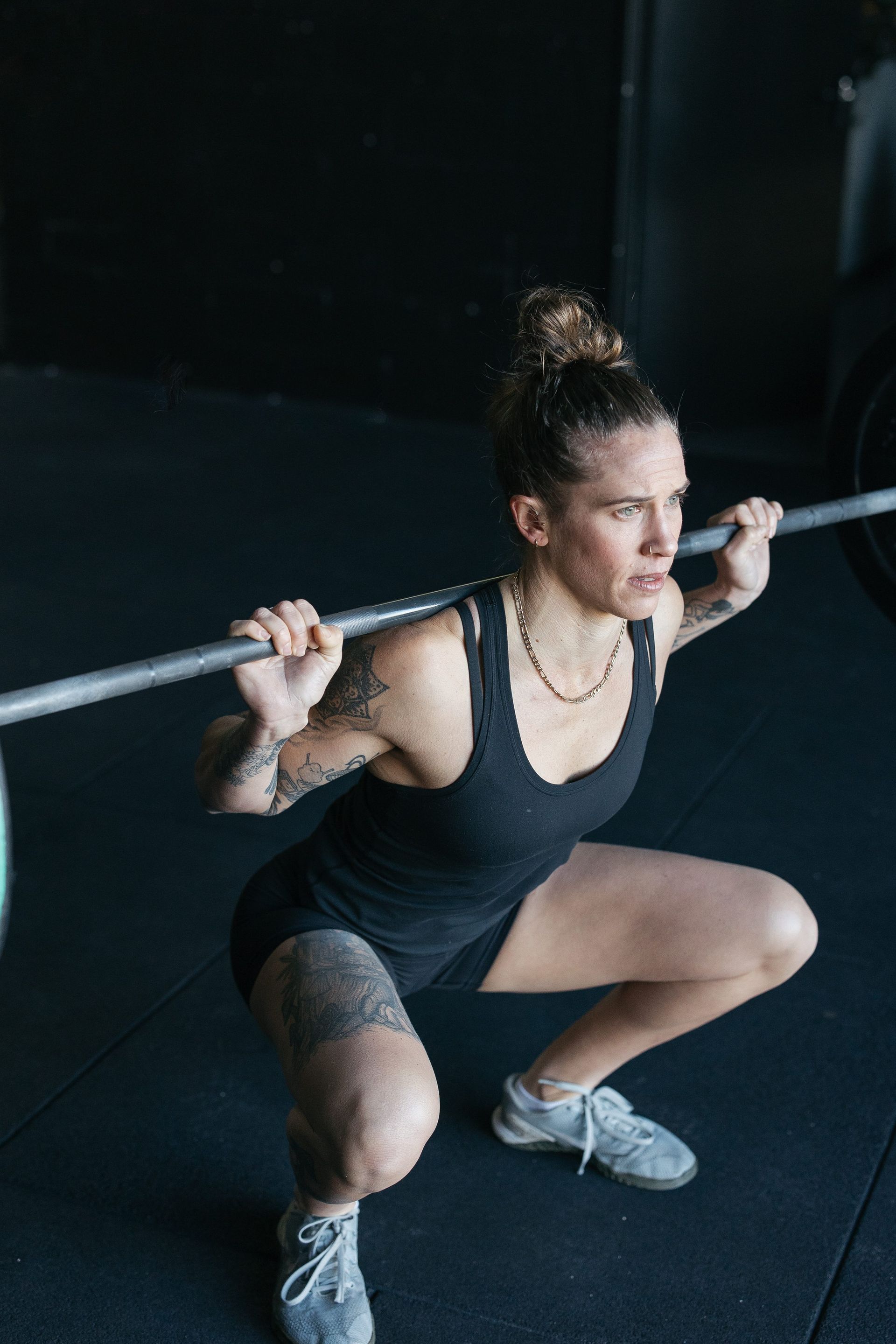 A woman is squatting with a barbell over her head in a gym.
