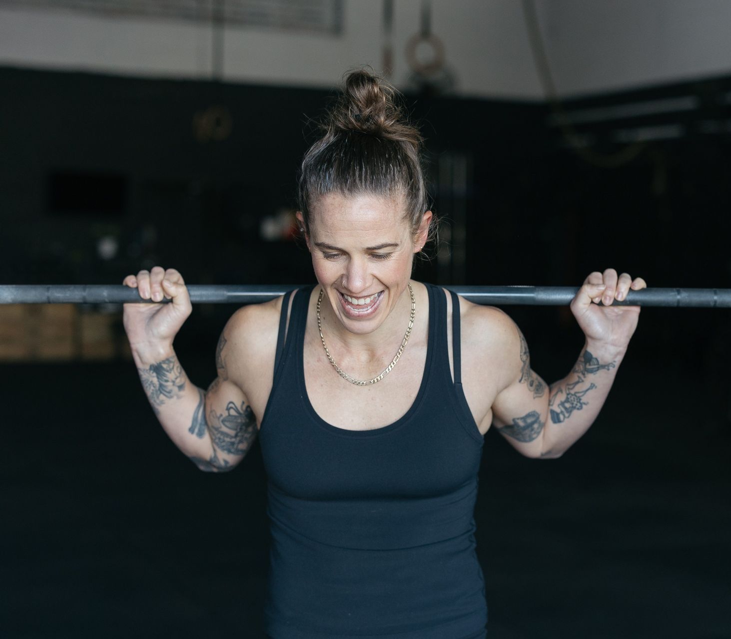 A woman is lifting a barbell over her head in a gym.