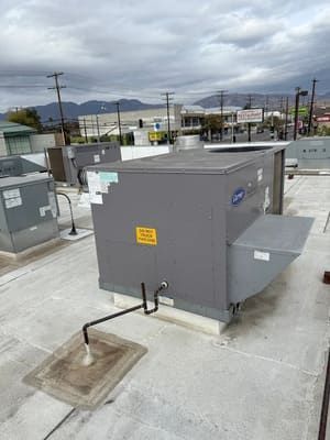 Gray electrical utility box and metal conduit on a concrete rooftop, with mountains in the distance.