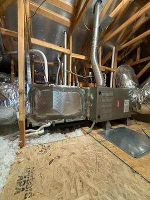 Attic HVAC furnace with ductwork, insulated vents, and exposed wooden framing under construction