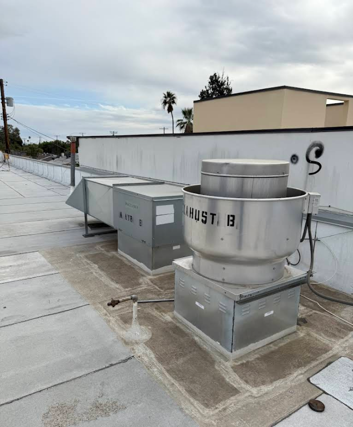 Rooftop HVAC vents and utility units on a flat commercial roof under a cloudy sky