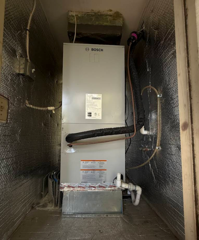 Bosch HVAC furnace in a narrow utility closet with foil-lined walls and exposed piping