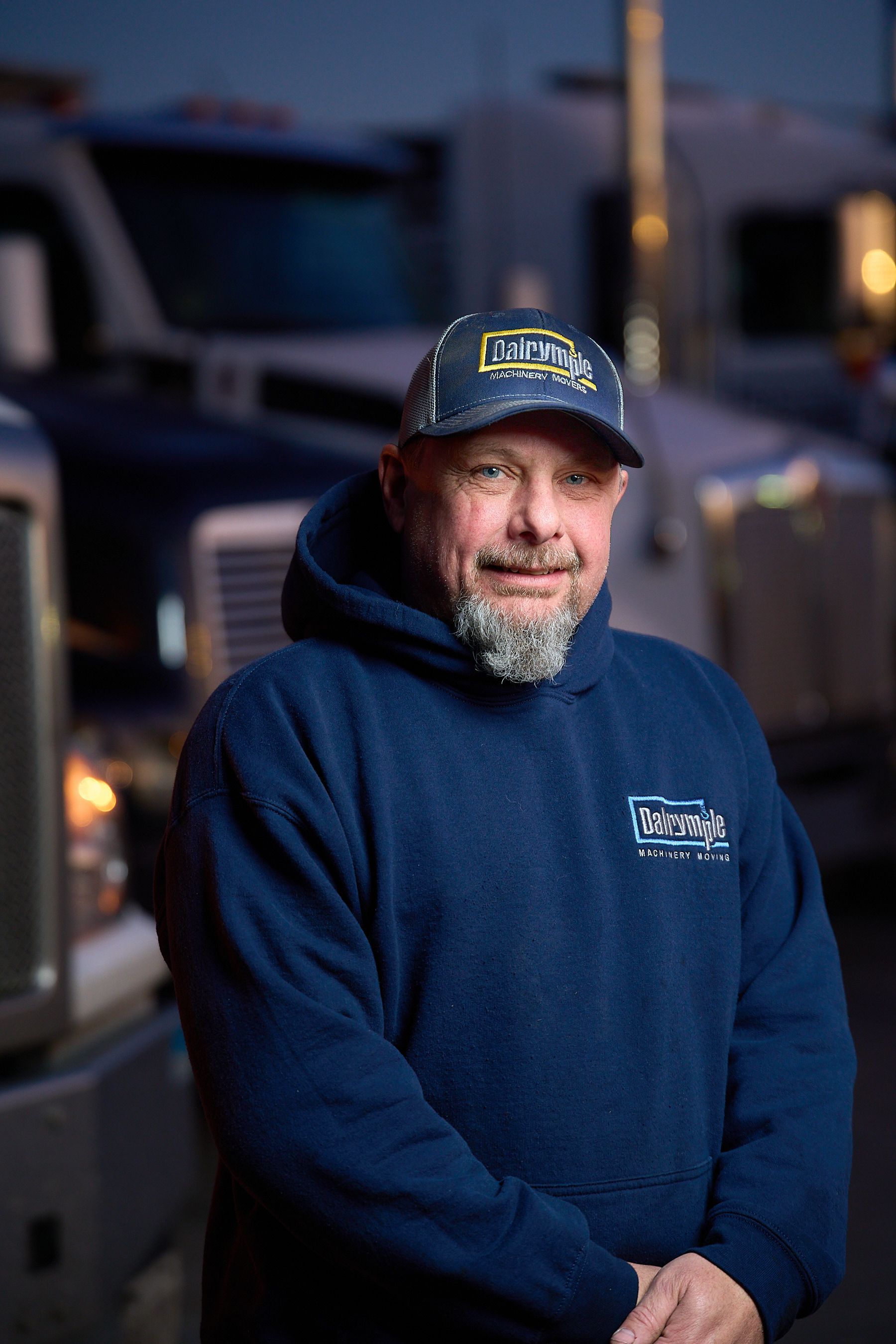 a man in a blue hoodie and hat is standing in front of a truck .