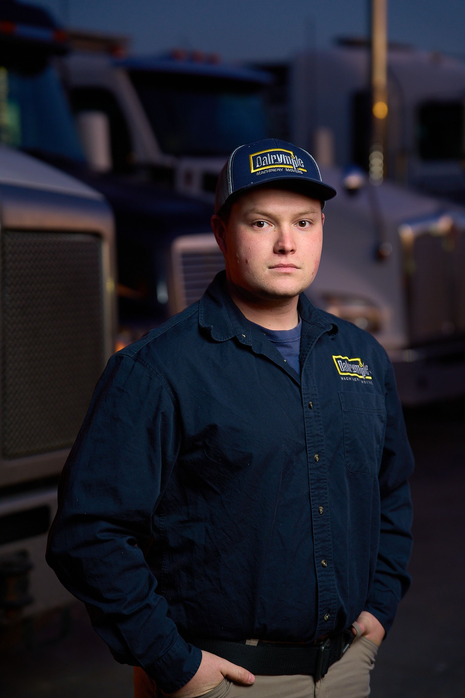 a man wearing a hat and a blue shirt is standing in front of a truck .