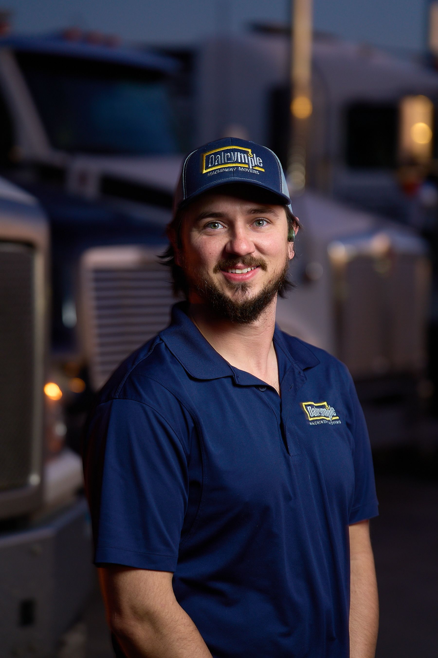 a man in a blue shirt and hat is standing in front of a truck .