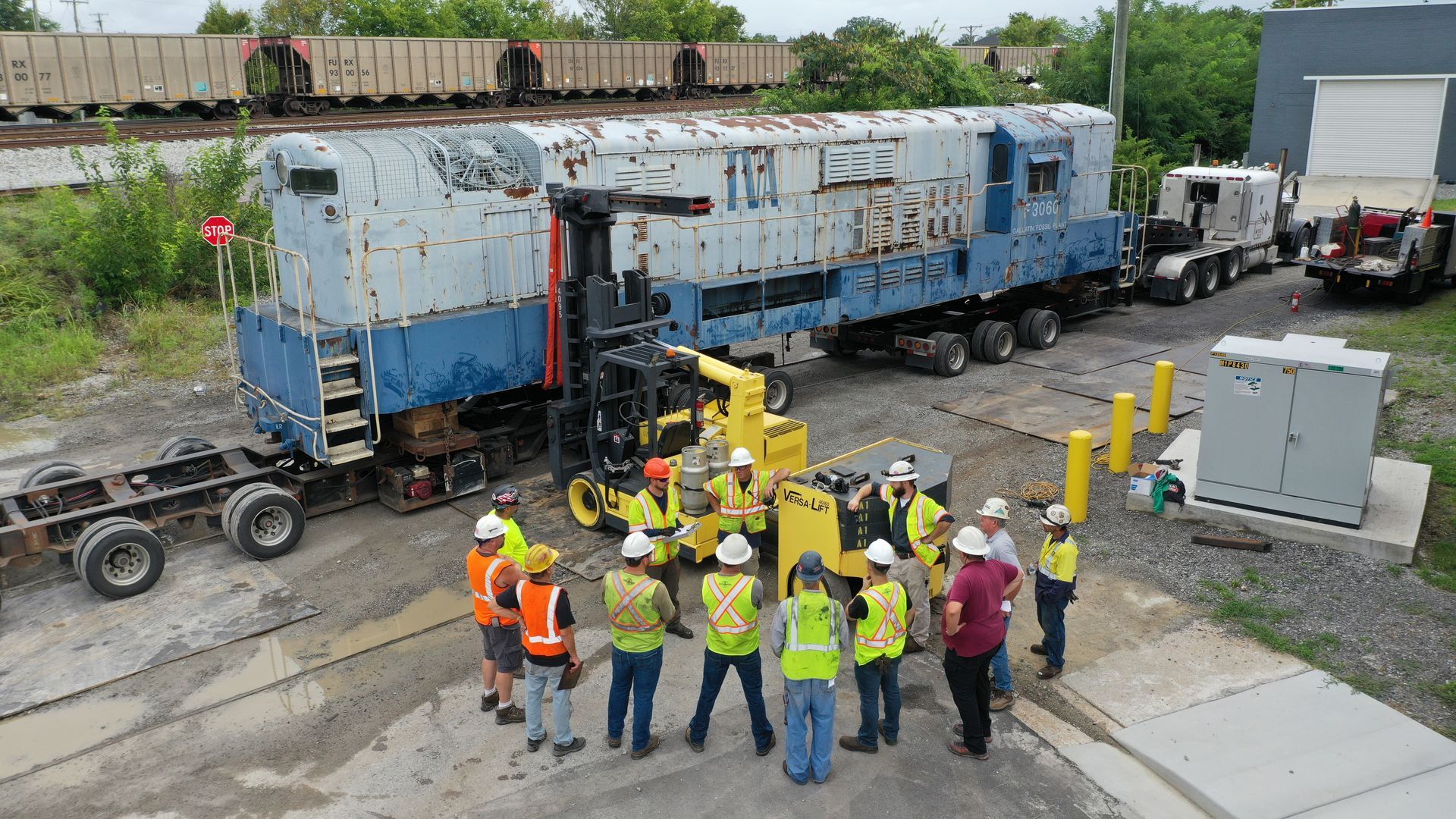 a group of construction workers are standing in front of a train .