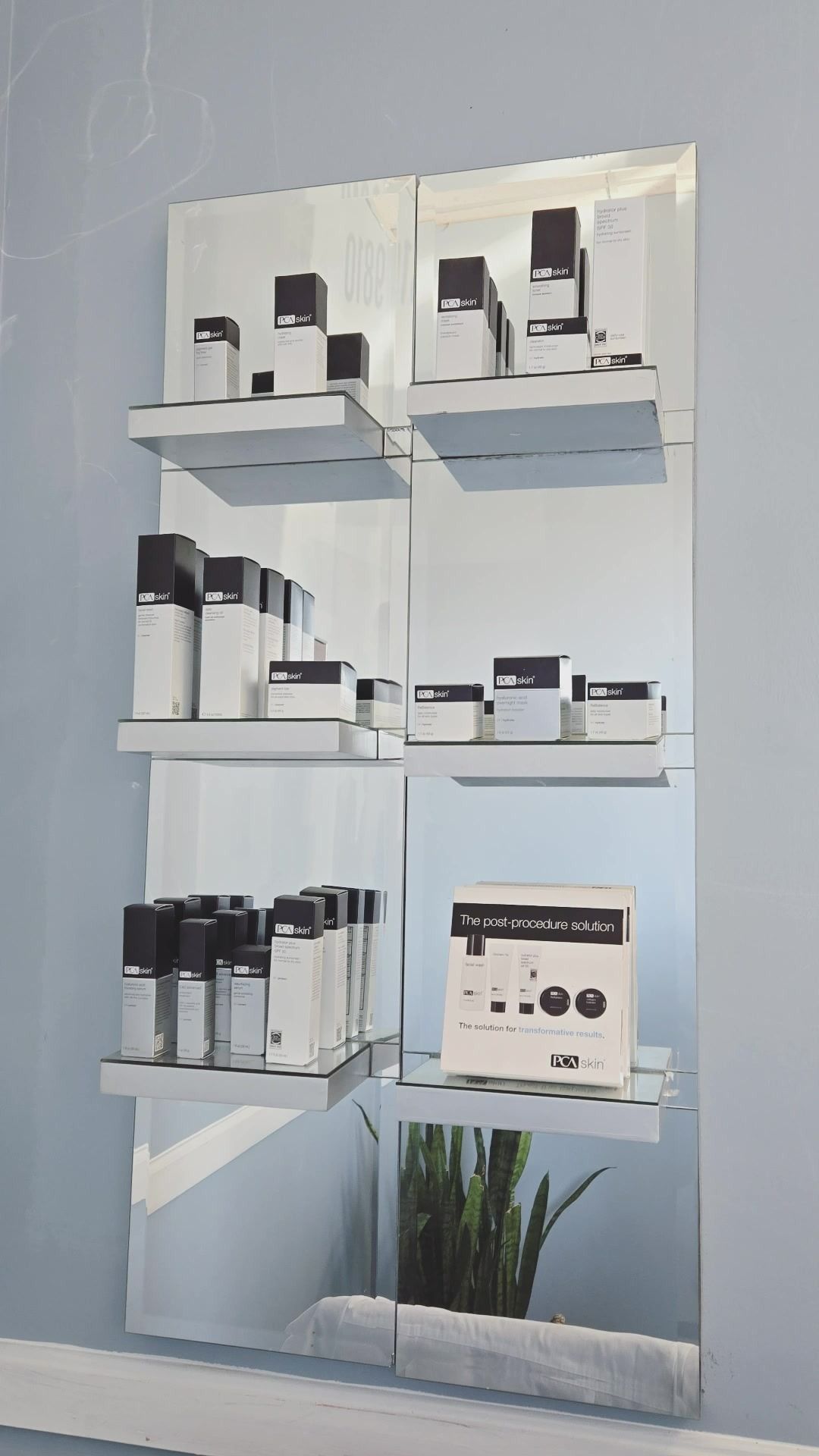 Shelves with skincare products on mirrored wall in a spa-like setting.
