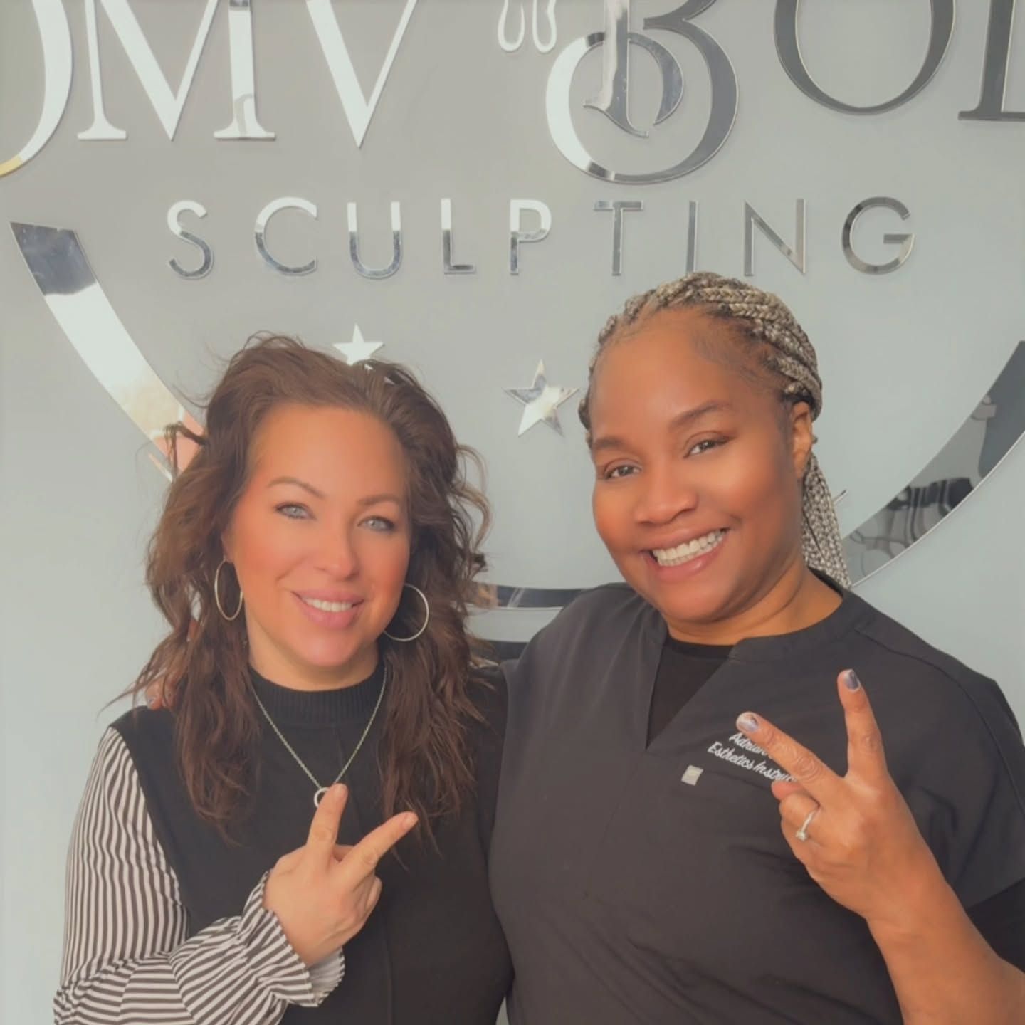 Two smiling women pose in front of a silver 