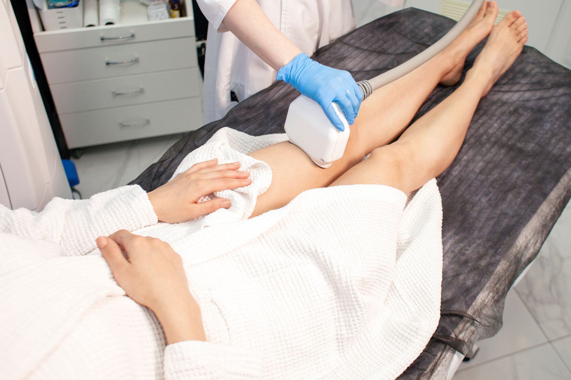 Person receiving laser hair removal on legs at a clinic.